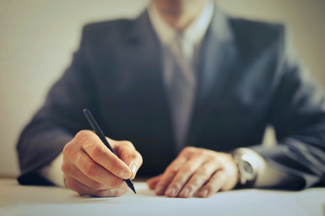 person in a suit looking over a contract